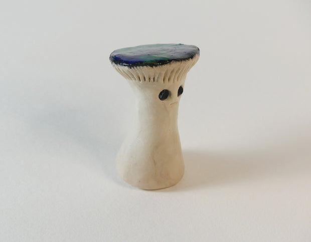 Sculpture of a mushroom with a thick based body and a flat shiny mushroom cap.