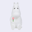 White Moomintroll character holding a pink flower on a light gray background