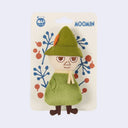 Plush toy of Snufkin from Moomin on a decorative card with floral patterns and Moomin branding.