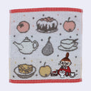 Hand towel with tea-themed design featuring a character, teapot, cake, and fruits on a white background.
