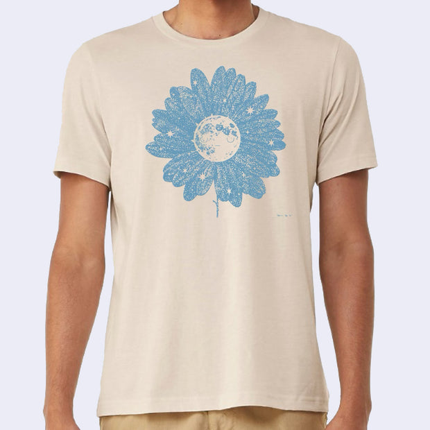 Tan t-shirt with an illustration of a moon with star patterned flower petals all around it. The moon has a simple closed eye expression.