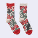 A pair of crew socks with a botanical pattern featuring red flowers, green leaves, and dark gray stems on a cream background, with solid red heels, toes, and cuffs.