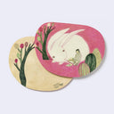 Rounded corner postcard (front and back design shown) with an illustration on front of a large bunny and small girl reading. Back design is of a curved tree.