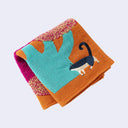 Folded colorful towel with a cat design on a light gray background