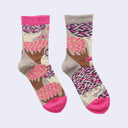 A pair of crew socks with a whimsical tree pattern in pink, brown, purple, and beige, featuring bright pink toes and heels, displayed against a light gray background.