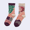 A pair of crew socks with a botanical and marine life print, featuring a green palm leaf, a red shrimp, and coral patterns on a light beige background with dark purple accents.
