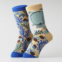 A pair of crew socks with a beige background featuring a blue, green, and brown coral reef and shell pattern, finished with solid blue heels, toes, and cuffs.