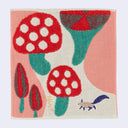 Fluffy square fabric towel with artistic illustrations of very large red spotted mushrooms and a small squirrel.