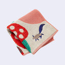 Folded fabric with mushroom and small squirrel design on a light gray background