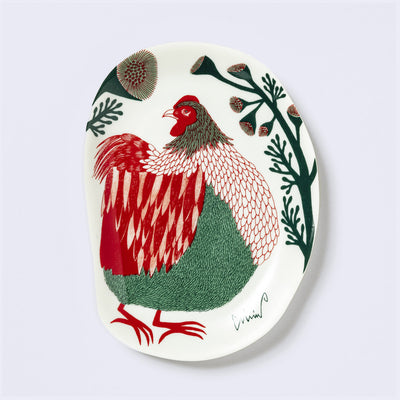 Decorative plate shaped like a slightly distorted oval with a rooster design and floral elements, in earthy tones of green and red. 