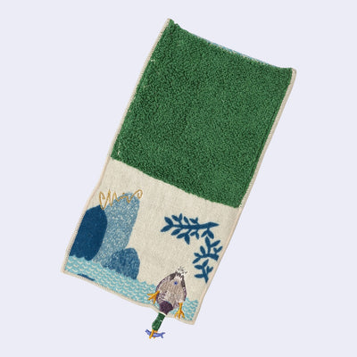 Rectangular textile with a pocket, the top can be folded over to make it into a pouch. Interior is green and exterior is beige with designs of a duck diving for a fish on water.