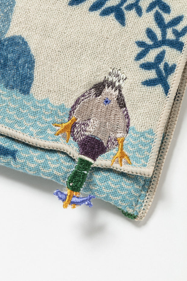 Embroidered detail of a pouch, a duck diving underwater for a fish which it holds in its beak.