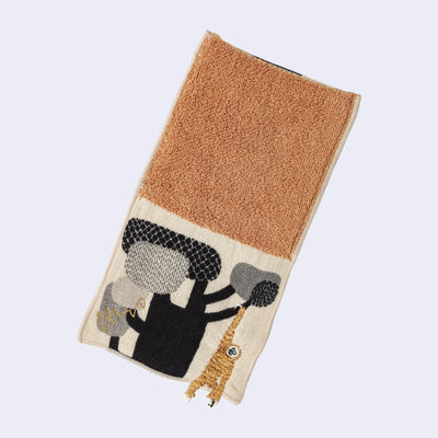 Rectangular textile with a pocket, the top can be folded over to make it into a pouch. Interior is orange and exterior is beige with designs of a gibbon hanging from a tree.