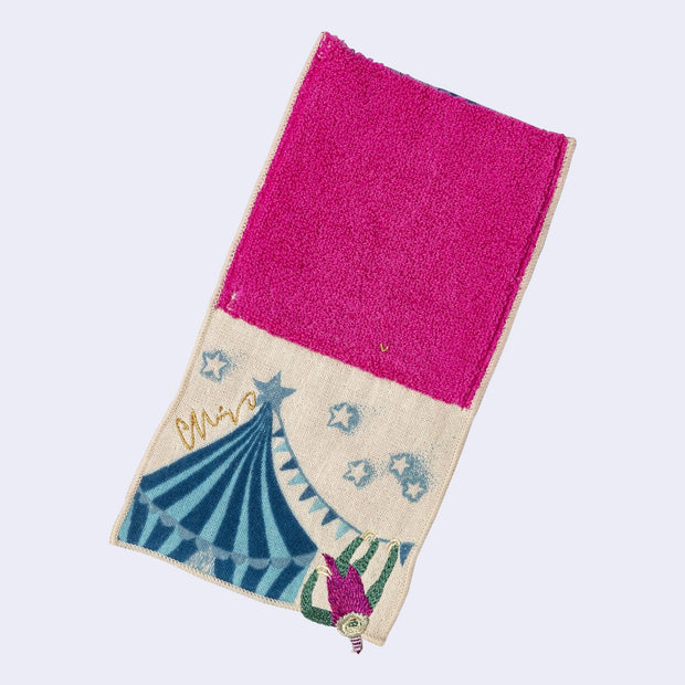 Rectangular textile with a pocket, the top can be folded over to make it into a pouch. Interior is bright fuchsia and exterior is beige with designs of a sloth hanging off of a circus tent.