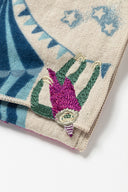 Embroidered fabric detailing of a sloth hanging upside down off of a circus tent.