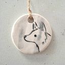 Round ceramic pendant with a wolf design on a textured surface