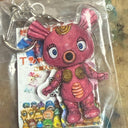 Pink cartoon character keychain with a clear plastic cover on a colorful background