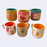 6 ceramic mugs with bright insides of all different colors, including yellow, orange, green, blue, or pink/red. Exterior of bowls have little drawings of foods, such as fruits or breakfast items.