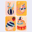 Four illustrated cards arranged in a 2x2 grid on a light gray background. Each card shows a whimsical circus-style character: a blue animal balancing on a striped ball, a pink mouse in a hat with a yellow balloon, a pink character wearing a striped hat with a red balloon, and an orange cat in a blue ruff on a red-and-yellow circus pedestal.