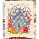 A hand holds a square art print featuring a whimsical fantasy illustration of a small figure standing before a large spotted creature, surrounded by colorful coral-like forms and dragonflies on an off-white background.