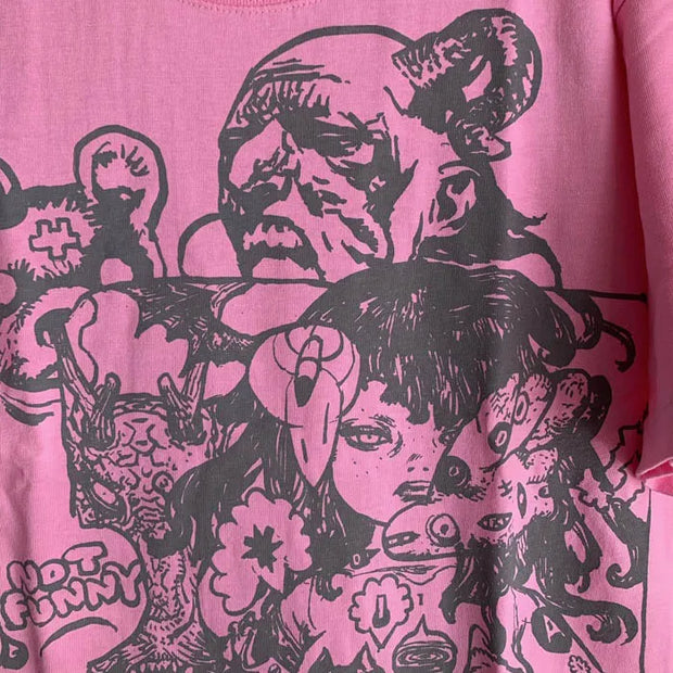 Pink shirt with a busy graphic on the front of art by Katsuya Terada, of a shirtless woman with mechanical body parts, an old man and a large bear that wears a shirt that reads "Not Funny." Close up.