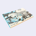 Side view of a memo pad with an illustration of a woman driving a car.