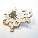 Die cut enamel pin designed by James Jean, of a white octopus outlined in gold with sparse gold swirl patterning, and a circular human like face, looking down. Its many arms are curled into itself and have light gold tentacles. Shown at an angle to display sheen.