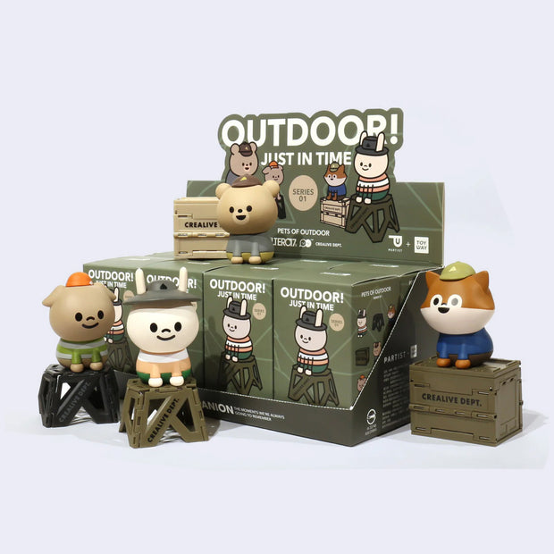 Several toy figures of cartoon animals dressed in outdoor gear, sitting next to their blind box packaging.