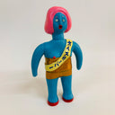 Toy figure with blue body, pink hair, and yellow sash on a white background