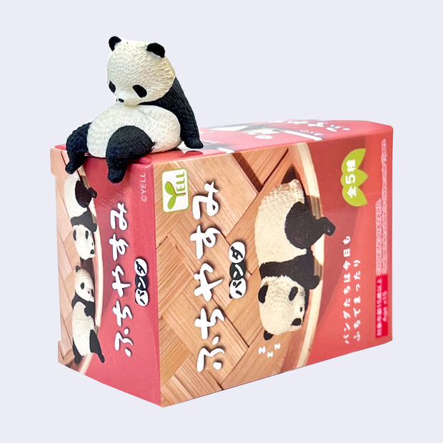 Panda figurine on top of a box packaging with panda illustrations and text.
