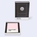 Pantone 182 card holder and packaging on a light gray background. The set includes a black-and-white Pantone-branded card holder box standing upright and an open white box containing a pink card labeled PANTONE 182.