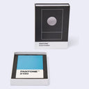PANTONE Card holder shown with its black-and-white branded box standing upright and the open box below, revealing a blue color card labeled PANTONE 2150.