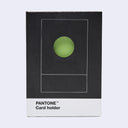 Pantone Card holder in its original packaging, featuring a black box with a white bottom band and a green circular cutout on the front.