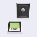 PANTONE Card holder in color 15-0343, showing the black and white packaging box alongside the open tray containing a light green card on a light gray background.