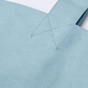 Close-up of a light blue canvas tote bag showing the fabric texture and a triangular stitched strap attachment.