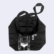 Black tote bag with interior slightly shown, displaying a snap button to close the top of the tote bag.