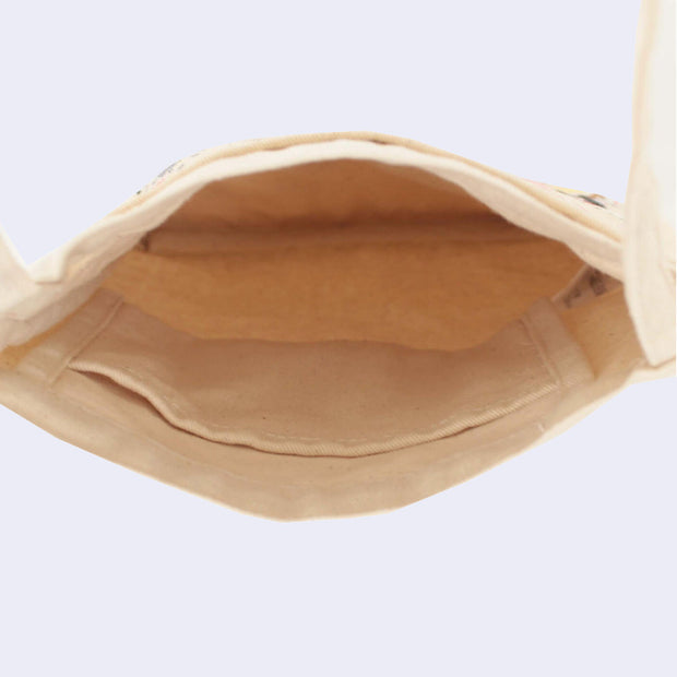 Interior view of a small, cream colored tote like shoulder bag with a main pouch area and a smaller pocket inside.