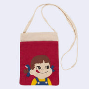 Cream colored small pouch bag with a red front pocket, featuring a graphic of Peko Chan, a small cartoon girl with overalls and pigtails who smiles with her tongue sticking out. Bag has a thin, long shoulder strap.