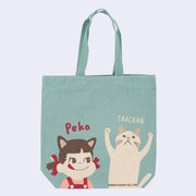 Teal tote bag featuring 2 illustrations at the bottom. One is Peko, a small girl in red overalls with pigtails tied in red ribbons and cat ears. The other is a white cat. "Peko" is written above the girl and "Taachan" above the cat.