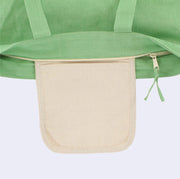 Close up of a green tote bag with a zip closure top, showing a cream colored inner pocket in addition to the main storage area within the tote.