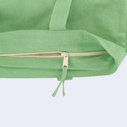 Close up, showing a green tote bag with a zipper closure at the top.