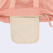 Close up of the top of a pink tote bag, with an additional cream colored interior pouch.