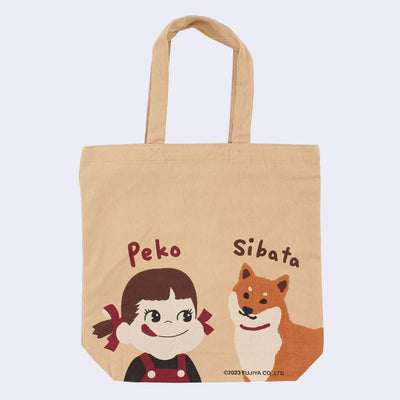 Tan tote bag featuring 2 illustrations at the bottom. One is Peko, a small girl in red overalls with pigtails tied in red ribbons. The other is a tan and white Shiba Inu dog. "Peko" is written above the girl and "Sibata" above the dog.