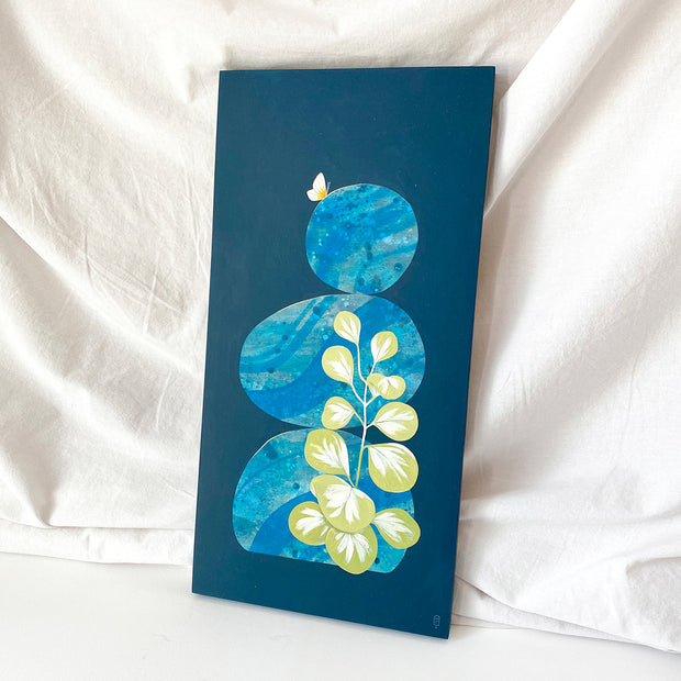 Collage style painting on a solid navy blue background of a stack of 3 rocks. Rocks have a bold abstract blue marble patterning on them, with a small yellow butterfly resting atop the top rock. A Peperomia plant reaches up to the top of the second rock. Displayed at an angle.