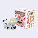 Animal figurine made to look like its carved out of wood and then painted, holding a crystal on its back and standing in front of its product packaging.