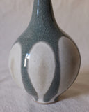 Vase with very skinny neck and slightly fluted top. Bottom of vase is white, top is bluish gray with dripping look.