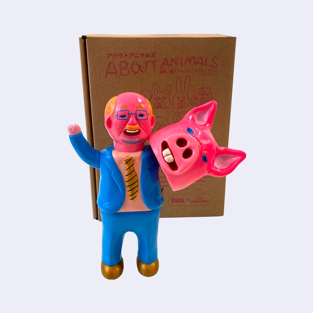 Neon pink vinyl figure of a business man, wearing a blue suit with gold tie and gold shoes. He holds a pink pig mask on one of its arms. It stands in front of its product packaging that reads "About Animals"