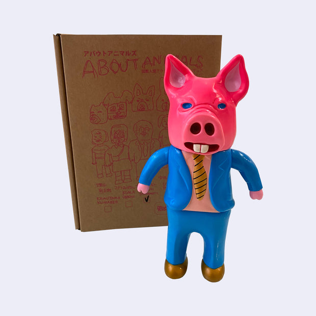 Neon pink vinyl figure of a business man, wearing a blue suit with gold tie and gold shoes. He wears a large pink pig head, completely covering his own head. 