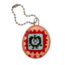 A small oval keychain or pendant with a glossy peach-orange border, red zigzag details, and a light blue center showing a black pixel-art character. A silver ball chain is attached at the top, photographed on a plain white background.