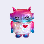 Pink and purple ombre soft vinyl figure with iridescent tinsel inside its body. Figure is shaped like a smaller Big Boss Robot, with a bigger head than normal and two black eyes with sparkles as pupils. A red heart is on its upper right chest.